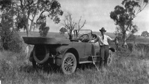 StateLibQld_2_128470_Fred_Eager,_holding_a_dead_goanna,_stands_beside_an_Overland_car,_1923