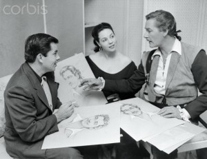 13 Jul 1952 --- Original caption: The Baroness Makes Up. Whims and whiskers are under discussion in this conference between Bud Westmore, (left), Mil Patrick, and Errol Flynn, the star for whom luscious Mil has sketched some beard styles. Her job of makeup designer is an important one on the lot. --- Image by © Bettmann/CORBIS